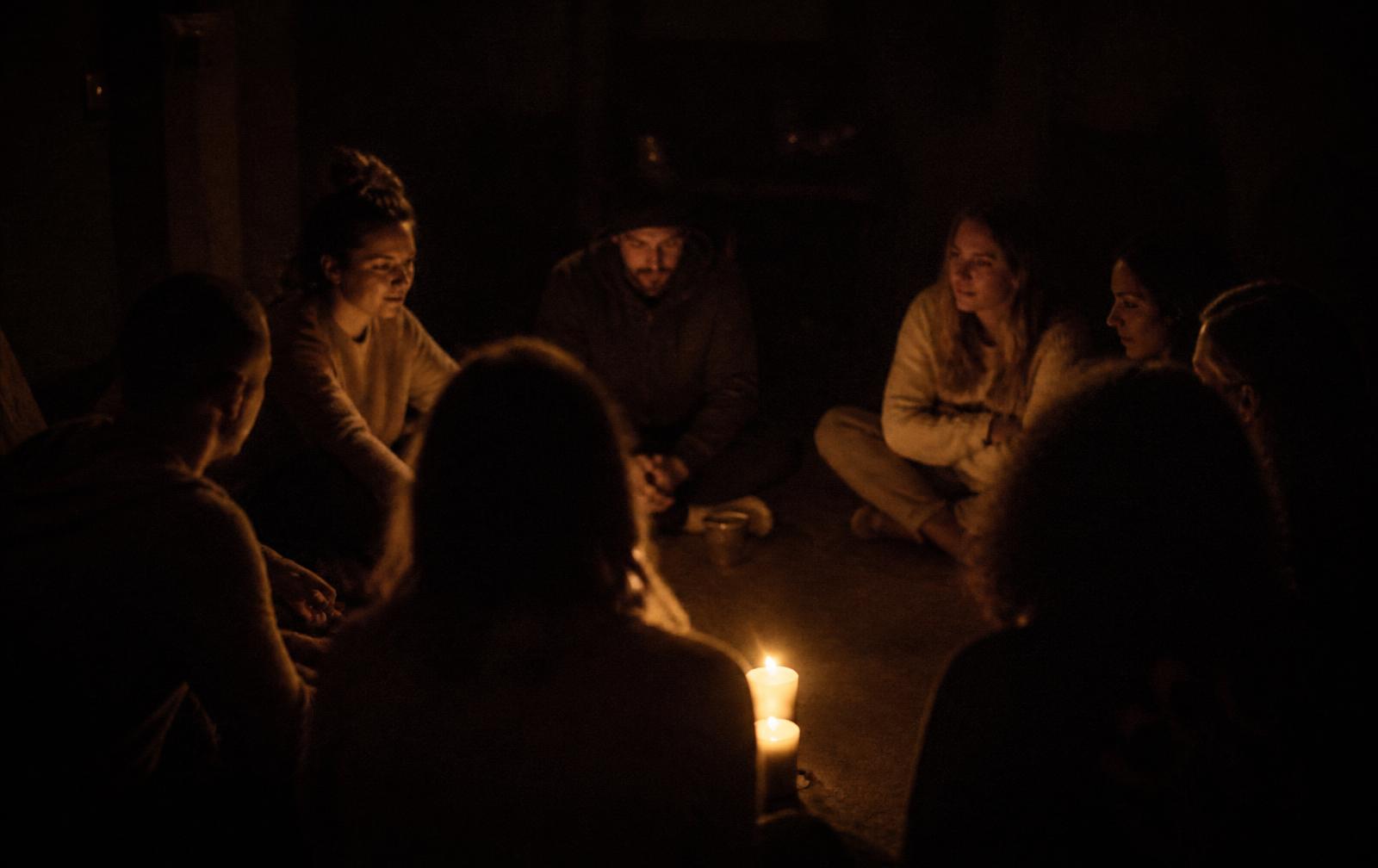 A small circle of people sitting together by candlelight